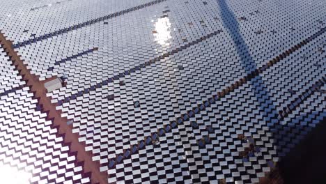 una toma inclinada de una granja de espejos solares térmicos con miles de espejos heliostáticos que reflejan la luz solar