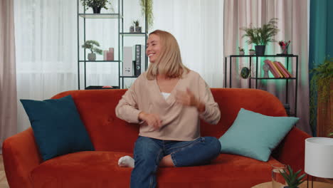 mujer alegre y positiva de moda bailando y moviéndose al ritmo haciendo un gesto de baile dub en el hogar moderno