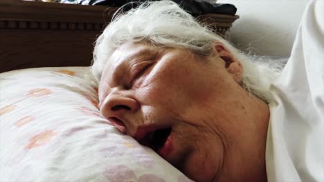close-up view of tired elderly woman sleeping in bed - handheld steady shot