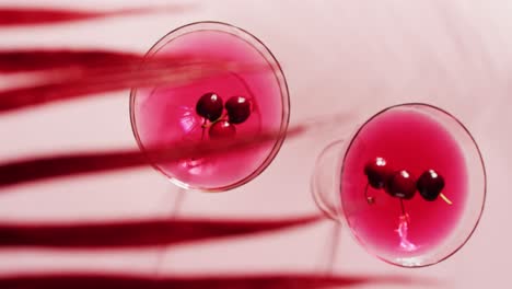 close up of drinks with cherries on white background