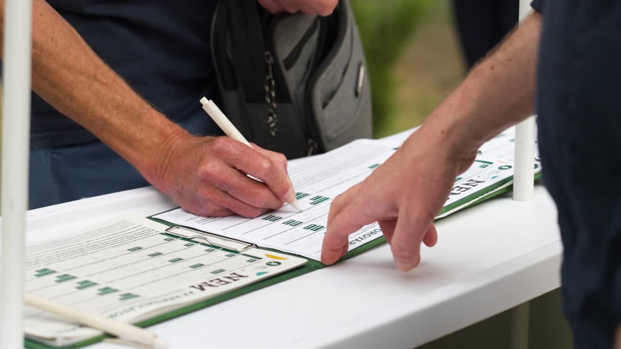 Close-up of a person signing documents outdoors at a table