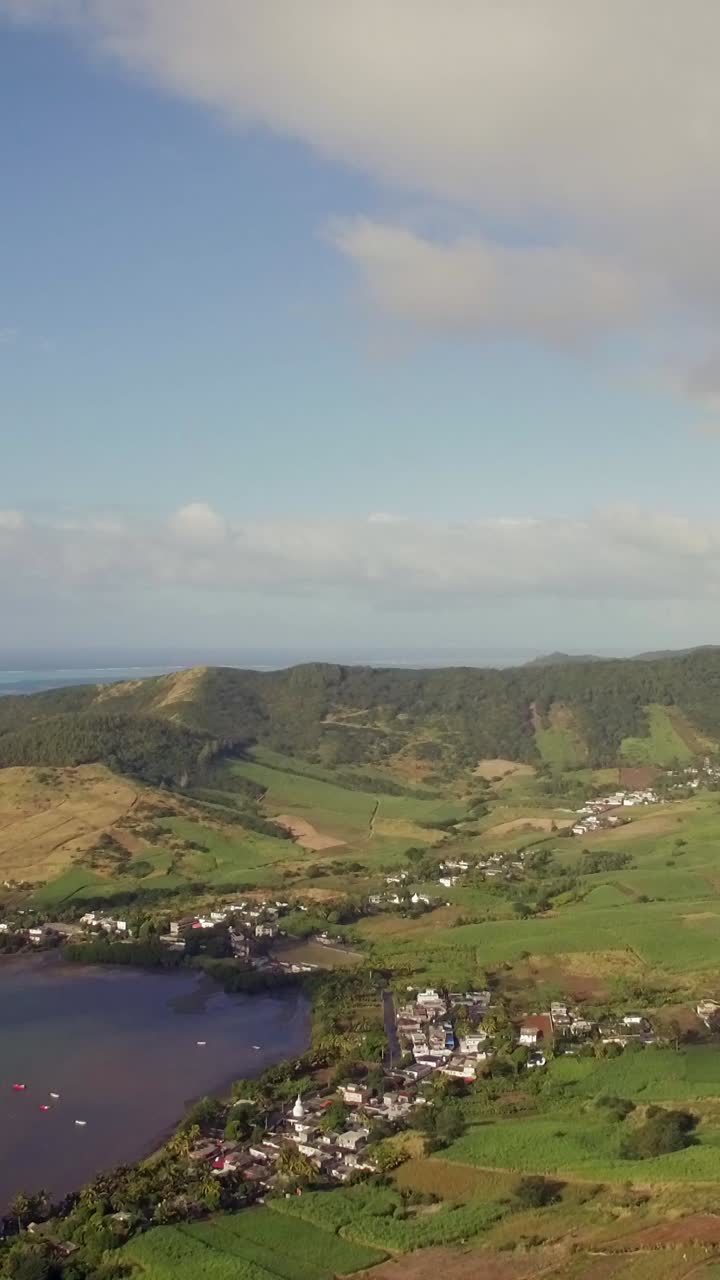 Vista Aérea Panorâmica de uma Vila Costeira e Colinas Verdes nas Maurícias