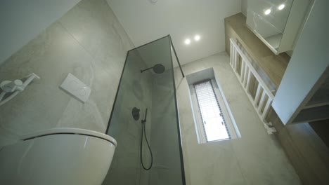 a sleek and modern bathroom featuring a glass-enclosed shower, wall-mounted toilet, and elegant marble tiles.