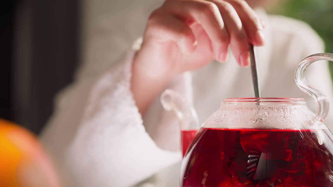 한 여인이 컵과 함께 차병에 히비스쿠스 음료를 니다. 한 여인이 식탁에서 아침 식사로 향기있는 허브 차를 습니다. 아침 의식에서 약혼합니다.