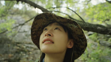 asian female hiker looking at trees in forest