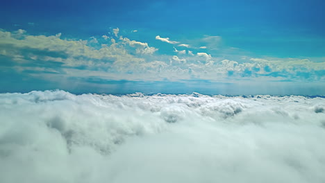 View during a flight over the rolling white cloud cover under a blue sky