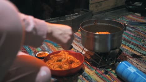 cooking pasta with a portable gas stove in a cottage in the nature, outdoor, camping