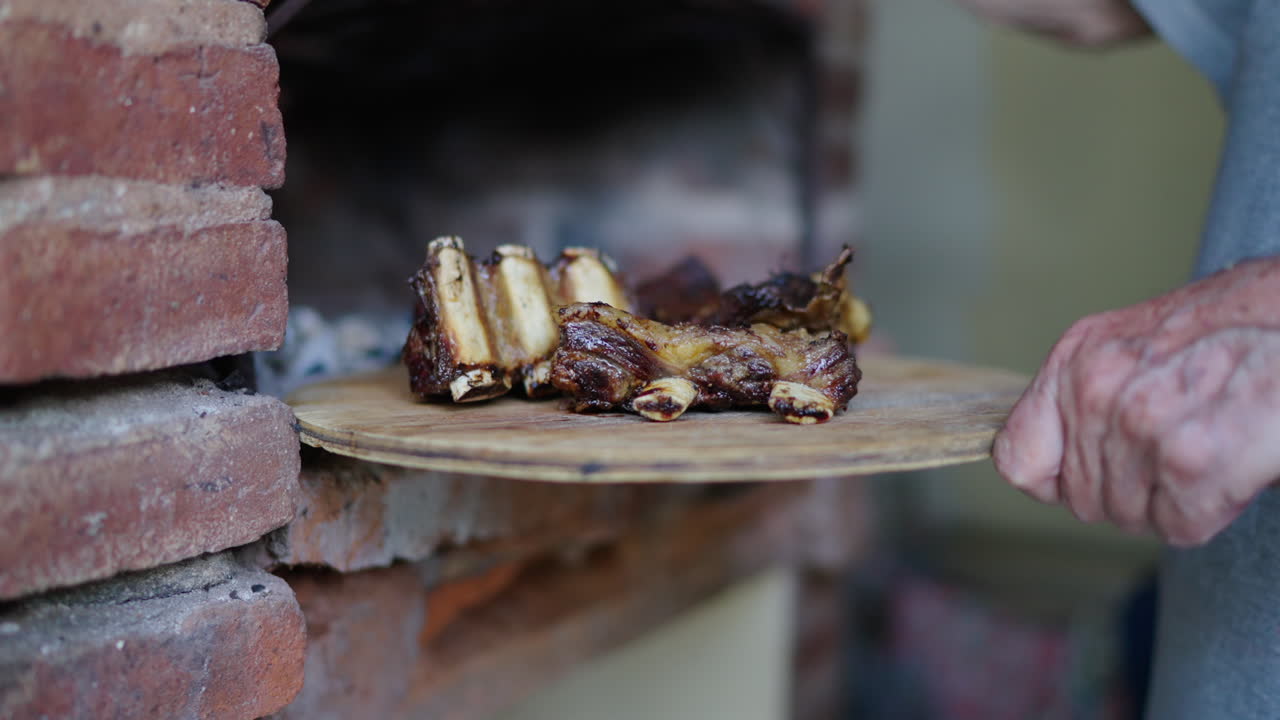 Traditional firewood barbecue ribs being seasoned in rustic outdoor kitchen