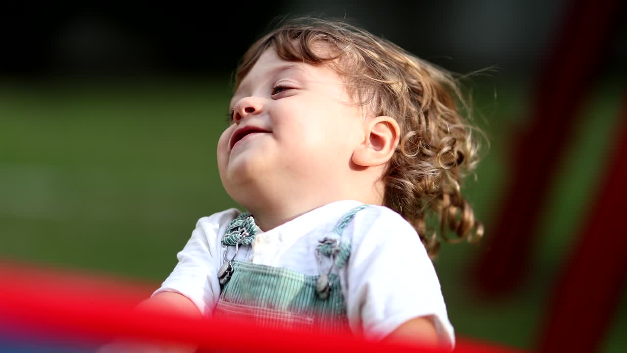 niño despreocupado girando en el carrusel del patio de recreo rostro sonriente de primer plano