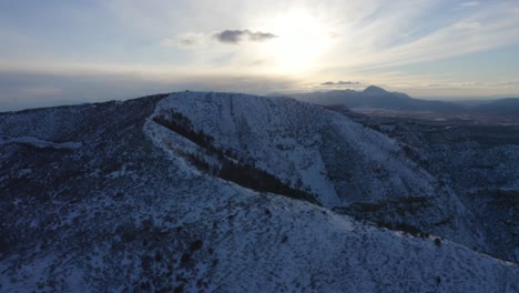 Beautiful-view-of-a-snow-covered-mountain-with-a-razor-sharp-summit,-surrounded-by-lush-vegetation,-with-the-sun-shining-brightly-in-the-sky