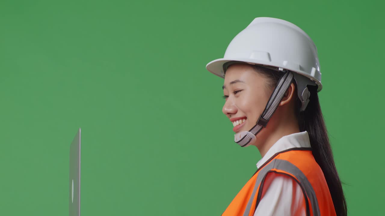 녹색 화면 배경 스튜디오에서 는 동안 노트북에서 작업하는 안전 헬을 입은 아시아 여성 엔지니어