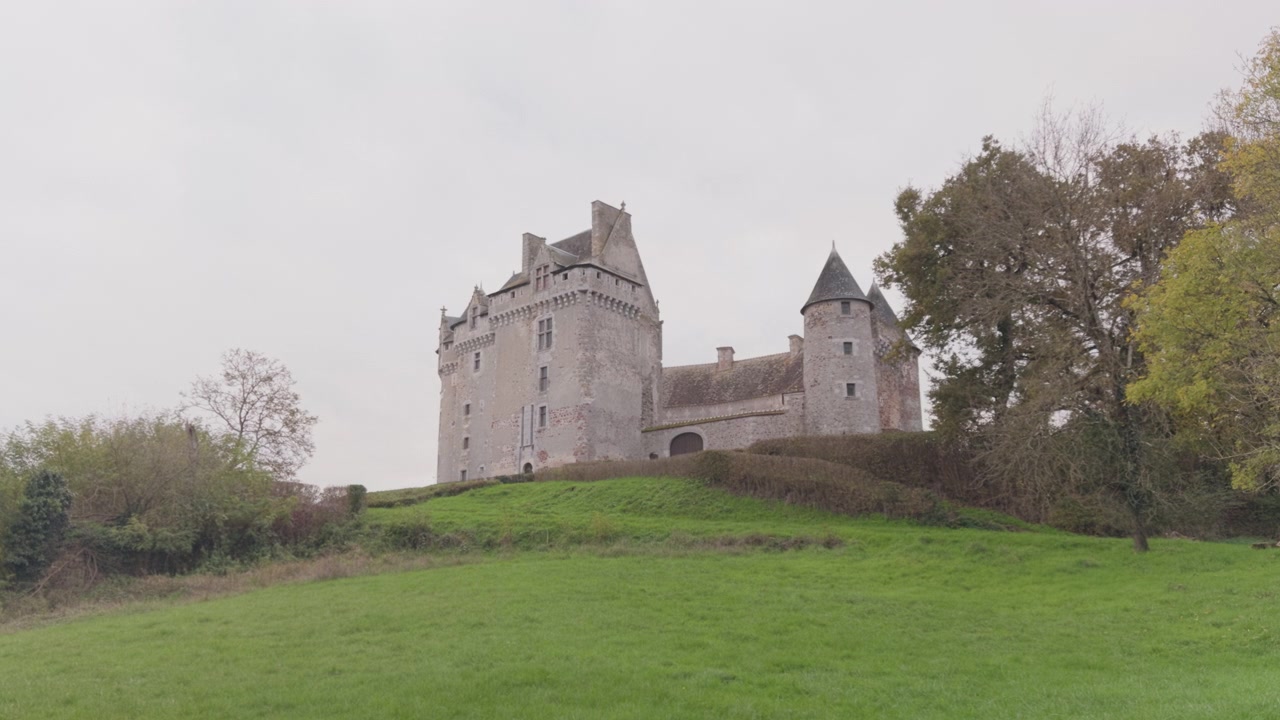 El Castillo de Bouchet se alza sobre una colina exuberante rodeada de árboles bajo un cielo nublado en Rosnay, Francia