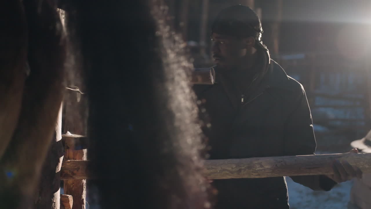 겨울 하늘 아래 말 옆에서 차분하게 지키는 사람, 얼음으로 뒤덮인 농장에서 보호 자세를 취하고 있는 고요한 사슴 관리인, 온화한 손길로 꽁꽁 언 헛간 배경에서 말을 지켜보는 평온한 관리인