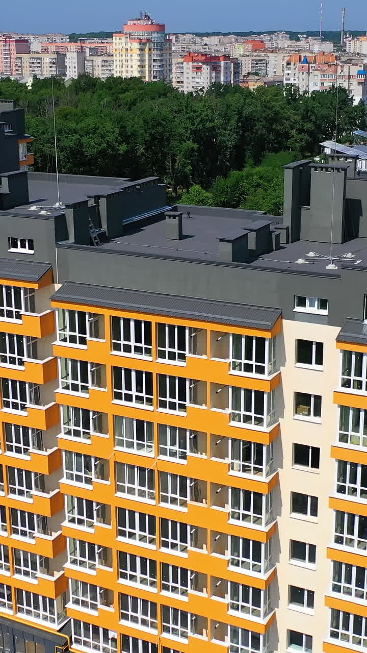 Exterior of modern architecture in the city. New apartment building with colorful walls and grey roof. Residential block of flats newly built. Aerial view. Vertical video