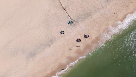drone top-down shot rotating above traditional round fishing boats on mui ne beach. the shot captures the boats, the sandy shore, and the gentle ocean waves creating a picturesque coastal scene.