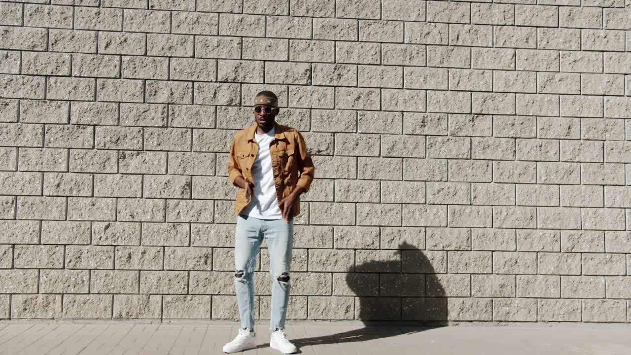 Stylish Man Dancing in Front of a Brick Wall