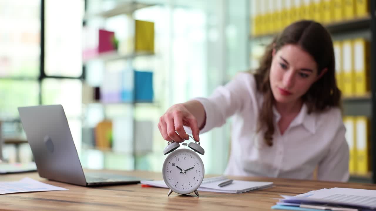 Woman interacting with an alarm clock at her office desk
