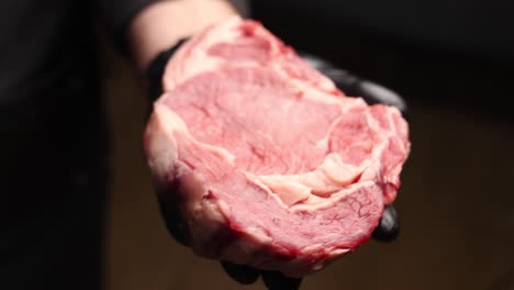 chef holding a raw rib-eye steak