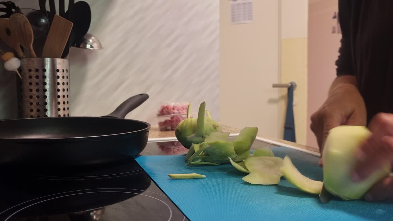 Healthy cooking at home, woman slices fresh kohlrabi (cabbage turnip) in her kitchen. Close-up of daily life, preparing nutritious meals with seasonal vegetables