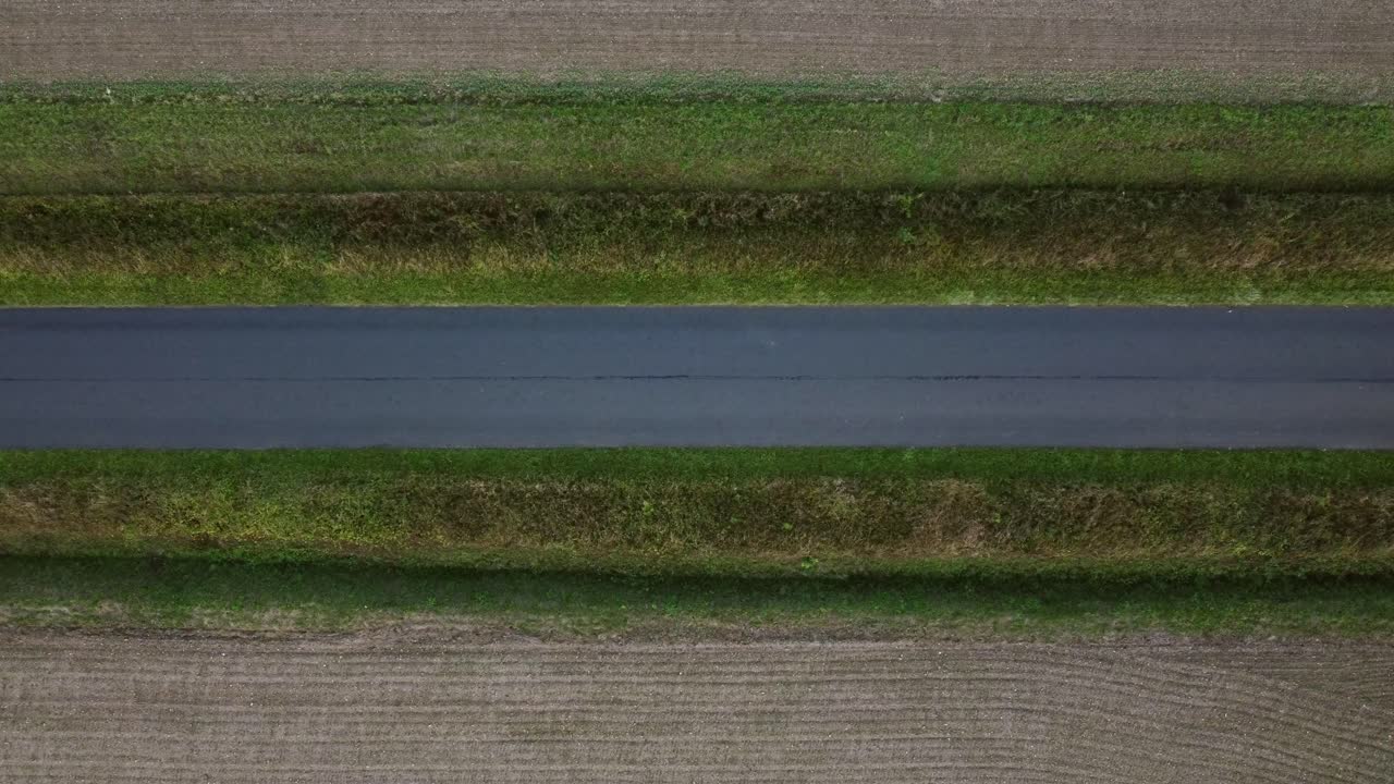 카메라에서 벗어난 시골길을 따라 빨간 자동차가 수평으로 운전합니다.