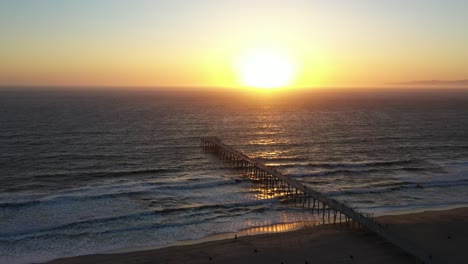 bright golden sunset over the sea with hermosa beach pier in california, usa