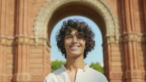 primer plano rostro de hombre feliz posando al aire libre. tipo sonriente cerca del arco del triunfo de barcelona