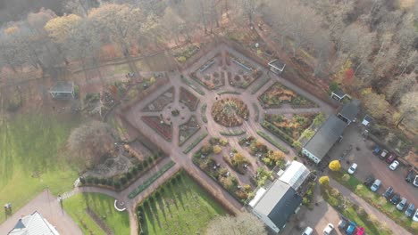 formal mansion gardens in autumn evening sun, drone flying high above