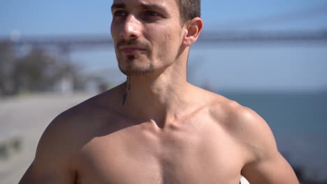 handsome muscular tattooed man jogging along embankment