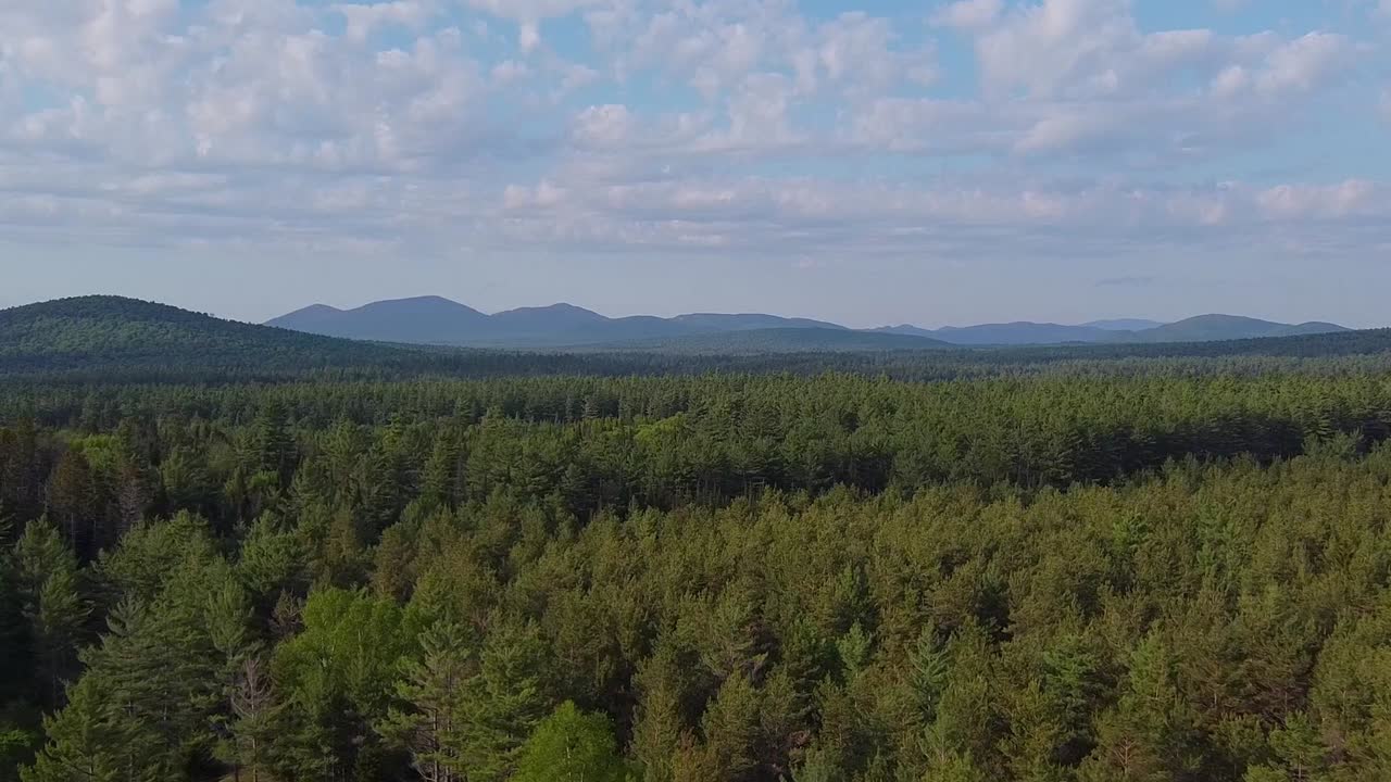 Ariel slow push over wilderness landscape with mountains and clouds in the distance