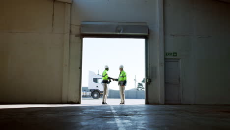 two warehouse workers shaking hands at loading bay