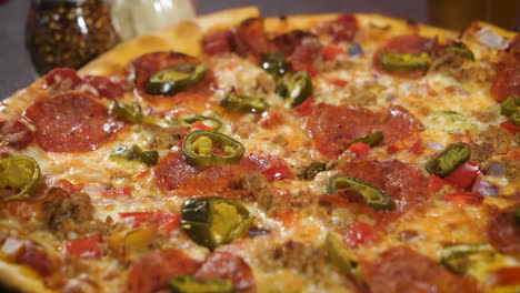 pizza de pepperoni y jalapeño de corteza fina, pizza entera en la mesa con queso rallado y agitadores de pimienta roja, cerca de 4k
