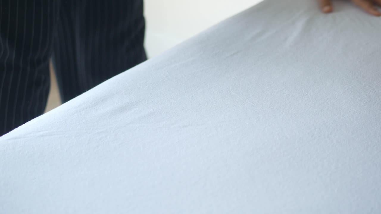 한 여인이 호텔 방에서 침대를 습니다.