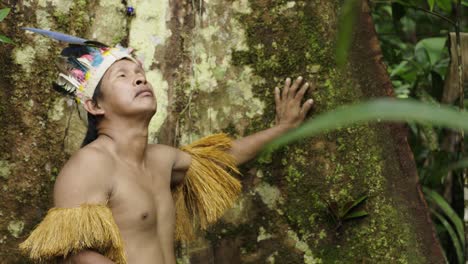 clips of an indigenous guy wearing a feathered hat and fringed shirt in the dense forest in amazon, leticia, colombia