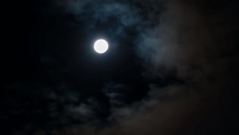 nubes a la deriva en el cielo. luna llena en el fondo.