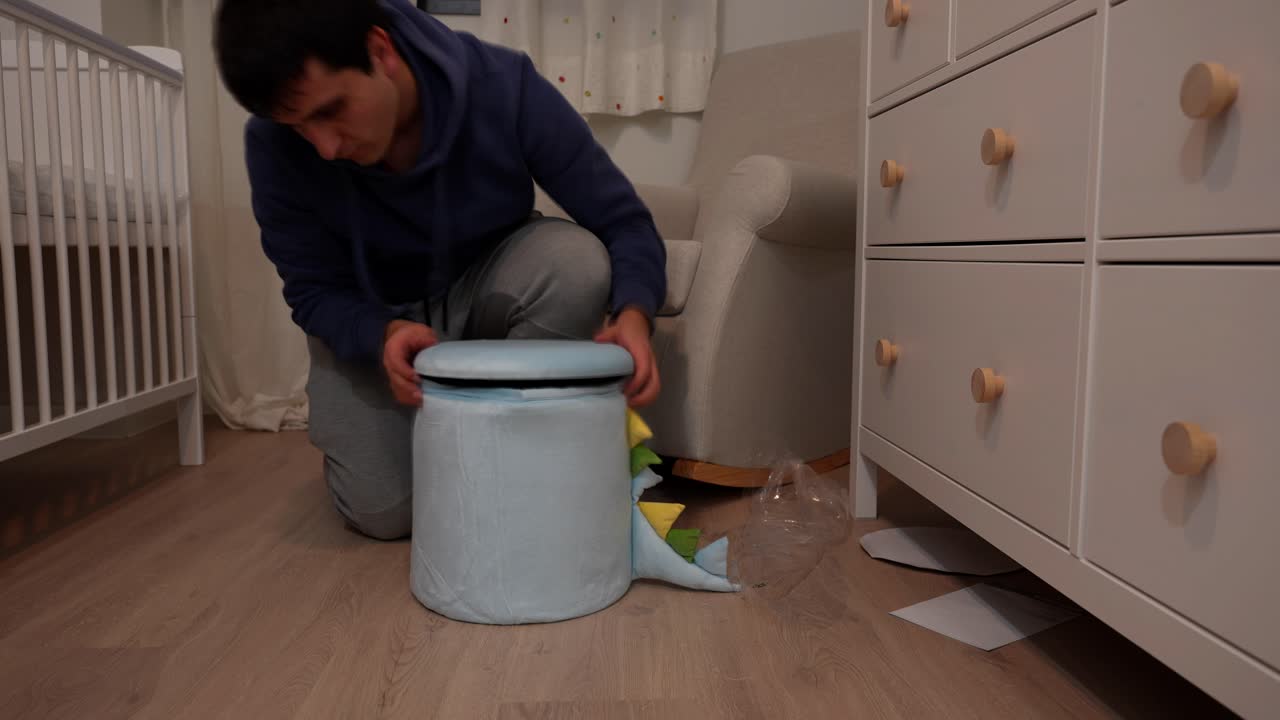 Man builds blue puff with dinosaur tail for baby's room in fast indoor nursery scene, timelapse