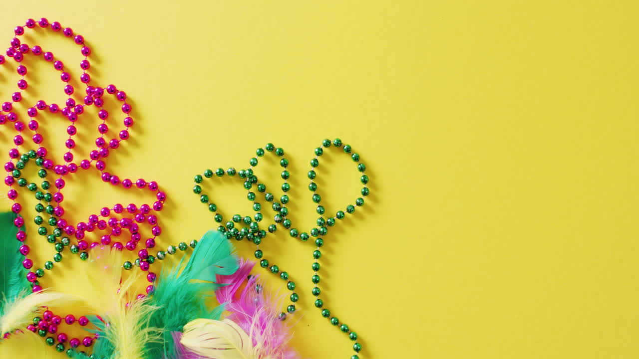 복사 공간과 함께 노란색 배경에 분홍색과 녹색 마디 그라 카니발 구슬과  ⁇ 털의 비디오
