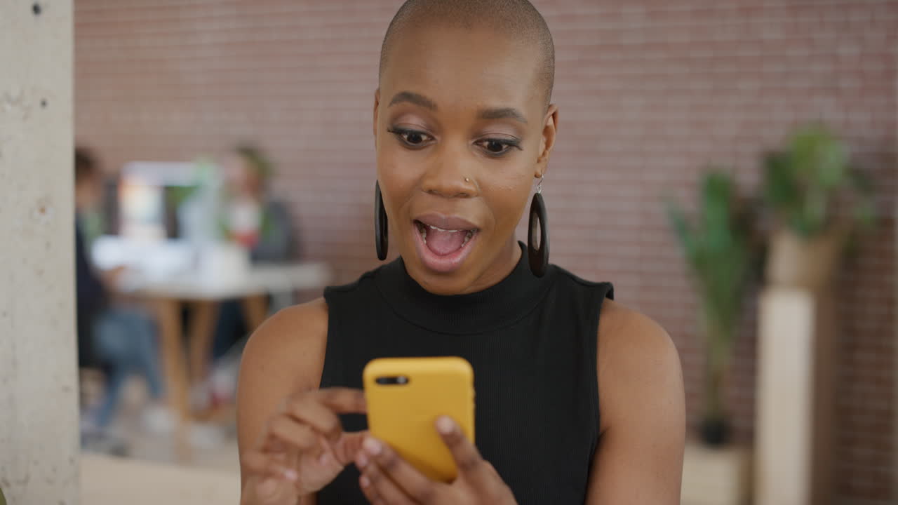portrait of african american woman using smartphone enjoying texting browsing online social media looking surprised mobile phone communication in modern office workspace