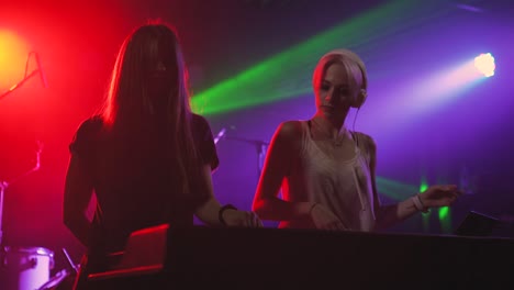 dos hermosas mujeres jóvenes dj tocan la música en la consola de mezcla en el club nocturno