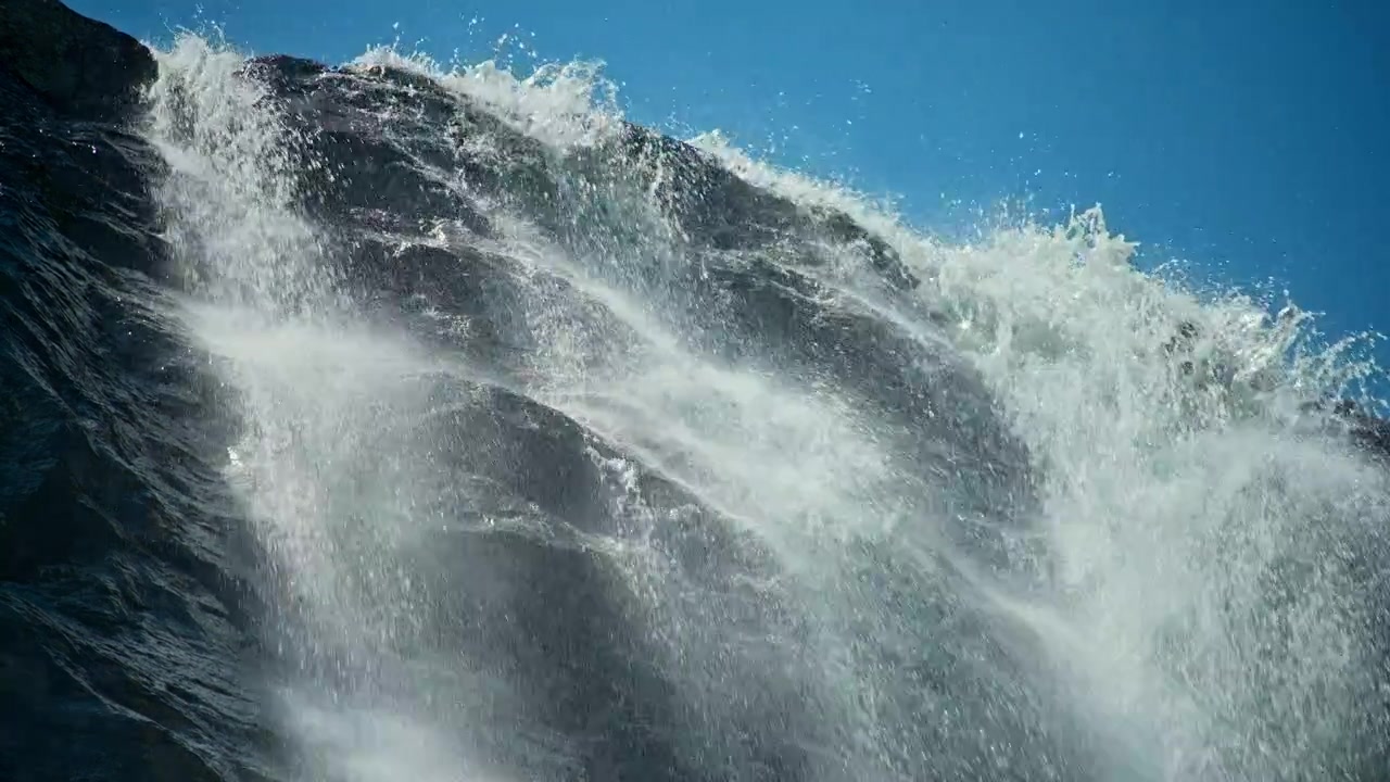 Powerful Waterfall Cascading Down Rocky Cliff Under Blue Sky