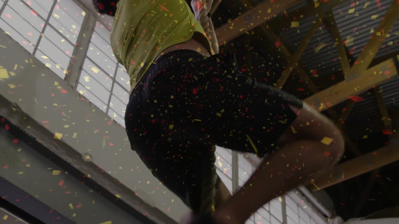 Climber grabbing rope, climbing in fitness gym to ceiling via leg clamp, particles showing watch