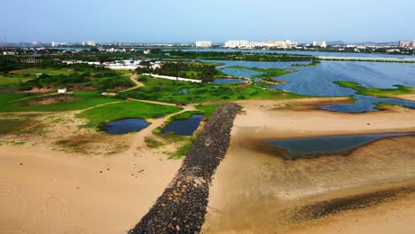 Drone-video-of-a-beach-with-waves-crashing-with-a-city-skyline-dotting-high-rise-buildings-in-the-backdrop