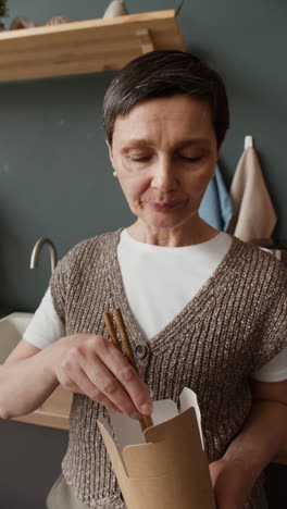 woman enjoying takeout noodles with chopsticks