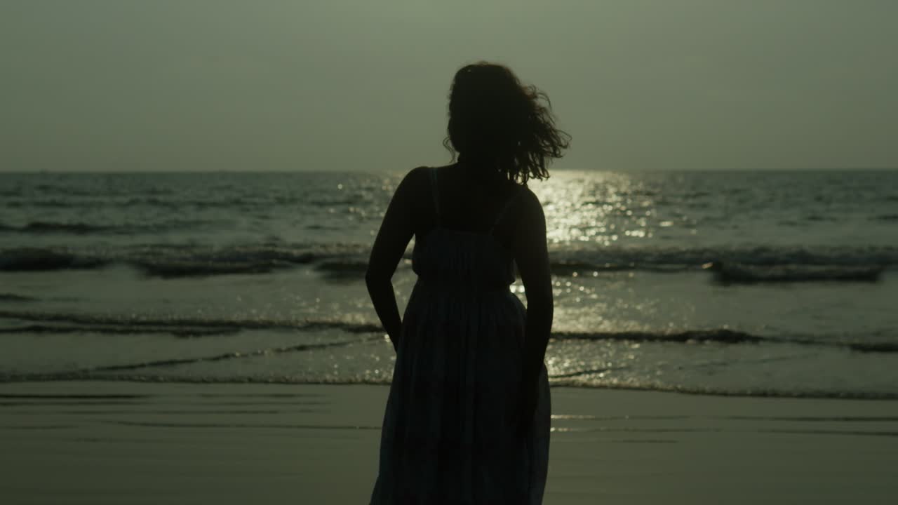 donna in piedi vicino al mare con i capelli che soffiano nella brezza