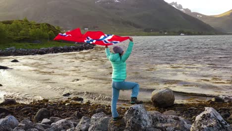 woman with a waving flag of norway on the background of nature