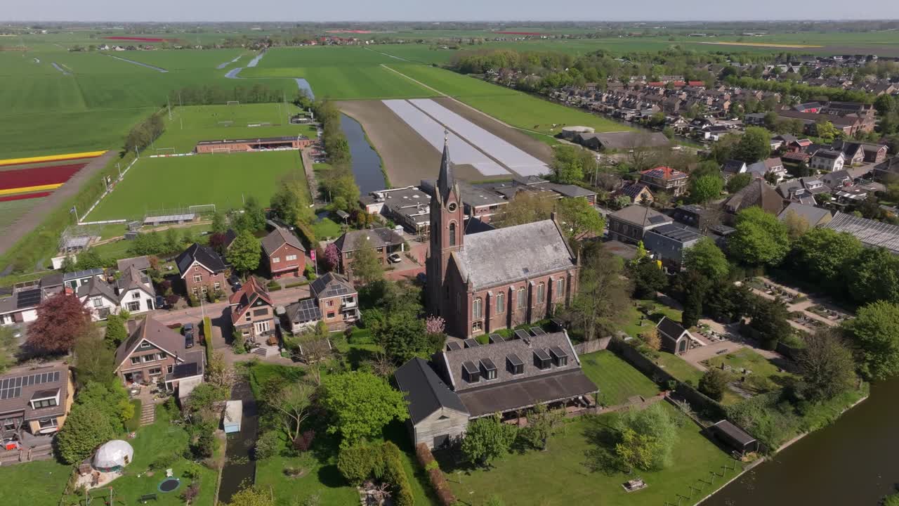 Luftfoto af Berkhout kirke omgivet af marker og huse i Holland.
