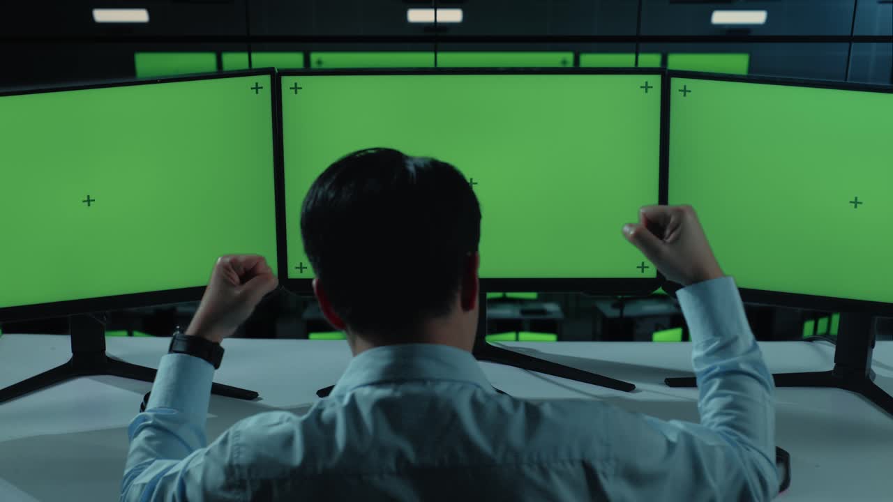 행복한 아시아 남자가 사무실에서 모의 여러 컴퓨터 모니터와 함께 일하면서 축하하고 춤을 추는 뒷면