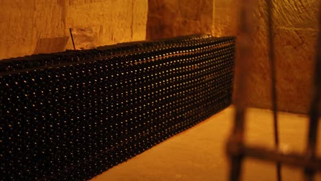 rows of wine bottles in a dim cellar