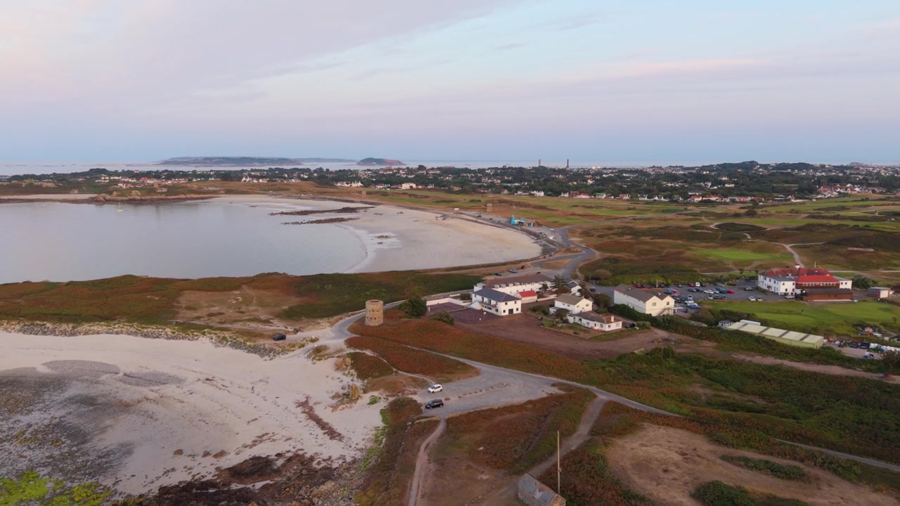 Baia di Lancresse, Guernsey, Isole del Canale. Lenta e ampia rivelazione dall'alto all'ora d'oro di tutta la Baia di Lancresse, Lancresse Common, La Joanneuse, campo da golf, club house e Herm, Jethou e Sark in lontananza