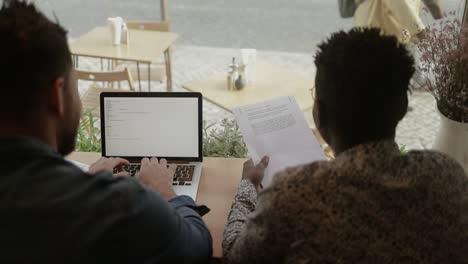 autónomos que trabajan con papeles y computadoras portátiles en una cafetería