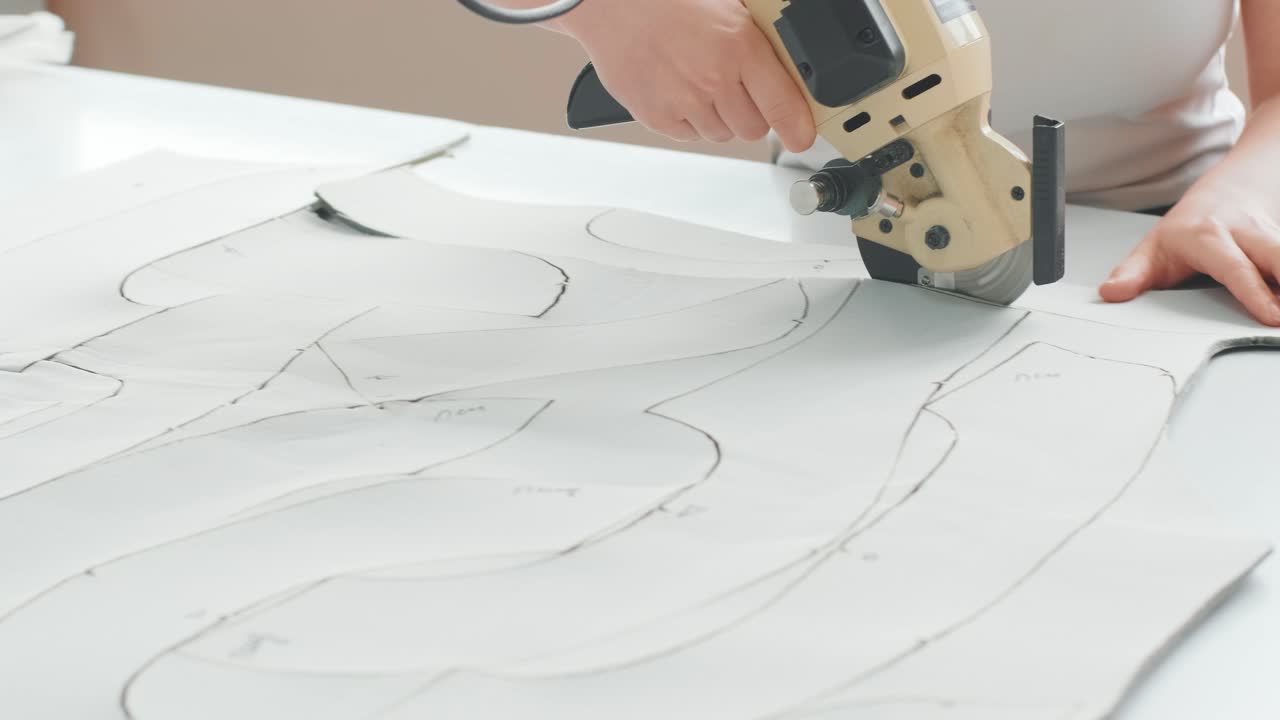 trabajadora de una fábrica de costura utiliza una máquina eléctrica para cortar telas. línea de producción de costura